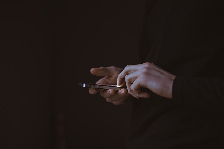 Hands using a smartphone in a dark room