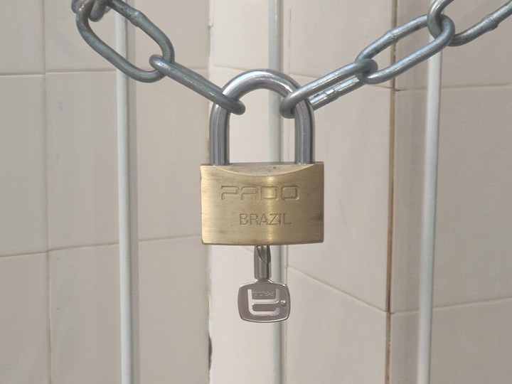 Brass padlock securing a metal chain