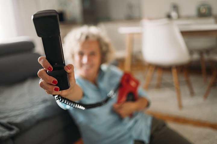 Hand holding out a phone receiver toward the camera
