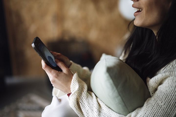 Woman smiling as she uses her smartphone at home